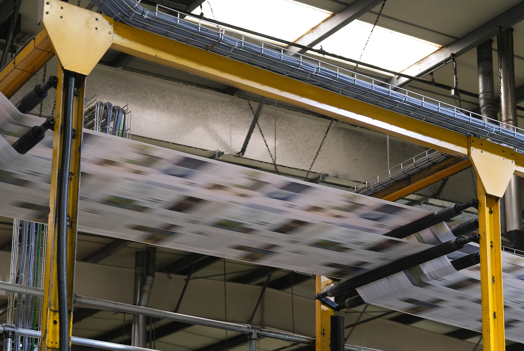 Freshly printed newspaper quickly advances through our large, traditional printing press.