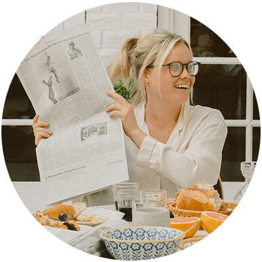 Margaux Reaume sitting at a table holding up a newspaper